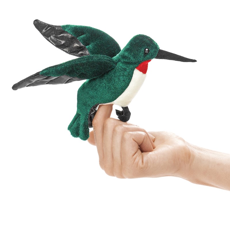 Folkmanis mini hummingbird finger puppet in green with a red throat and black wings, worn on an index finger, side view