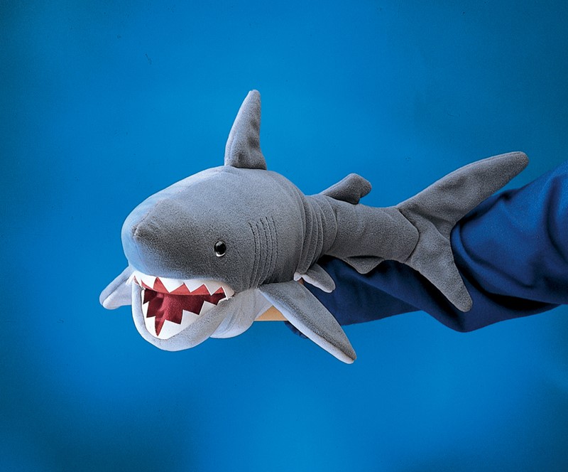 Folkmanis shark hand puppet in grey with open mouth and jagged teeth, worn on a hand, side view against a blue background