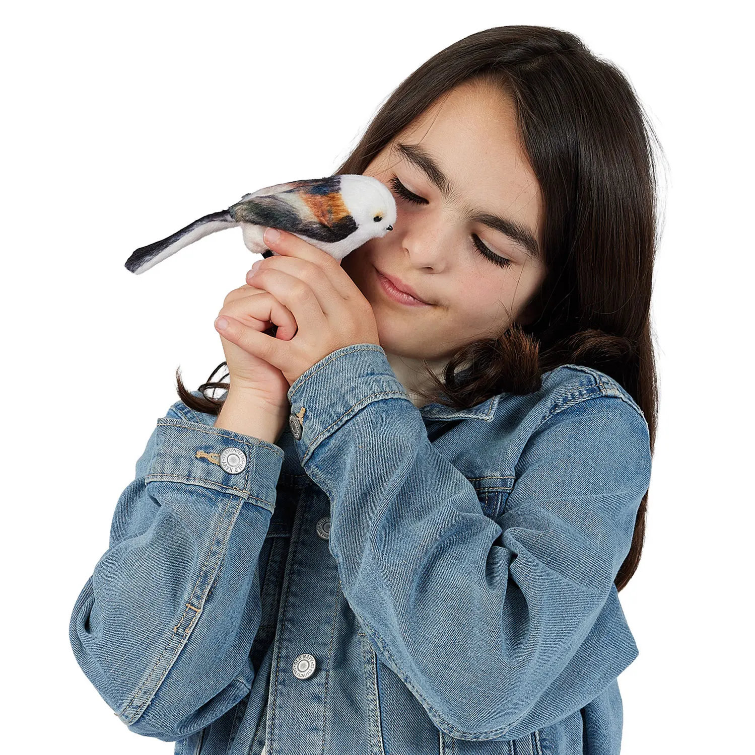 Girl holding a Folkmanis mini long-tailed tit finger puppet with a white head and russet plumage close to her face, eyes closed