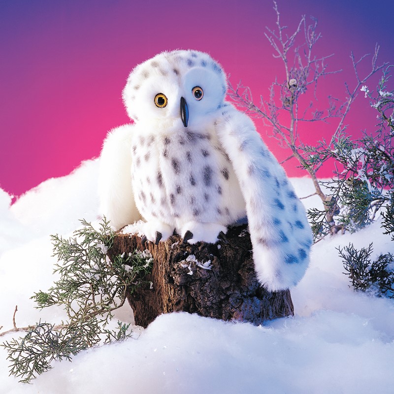 Folkmanis snowy owl hand puppet in white plush with grey spots, sitting on a tree stump in the snow