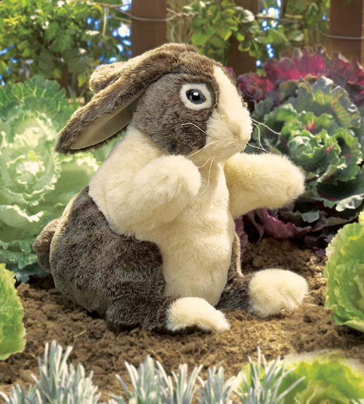 Folkmanis hand puppet Dutch rabbit with brown fur and white chest, sitting upright in a vegetable garden