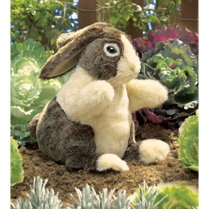 Folkmanis hand puppet Dutch rabbit with brown fur and white chest, sitting upright in a vegetable garden