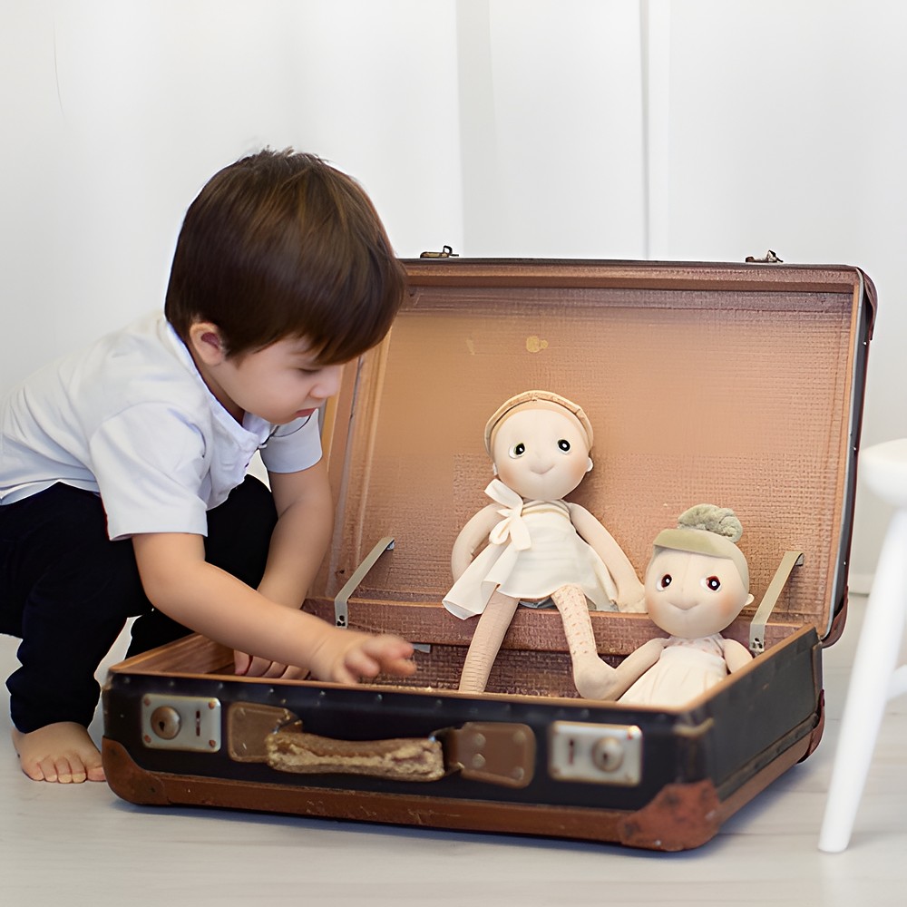 Child unpacking the Rubens EcoBuds dolls from an old travel suitcase