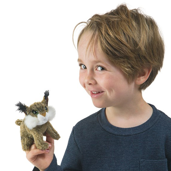 Smiling child holding a small Folkmanis Mini Bobcat finger puppet with tufted ears and white muzzle area on their index finger
