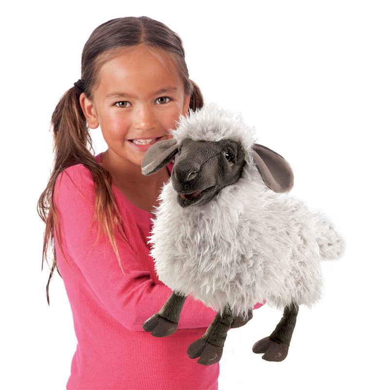 Girl holding a Folkmanis hand puppet bleating sheep with white plush fleece, dark face and movable mouth
