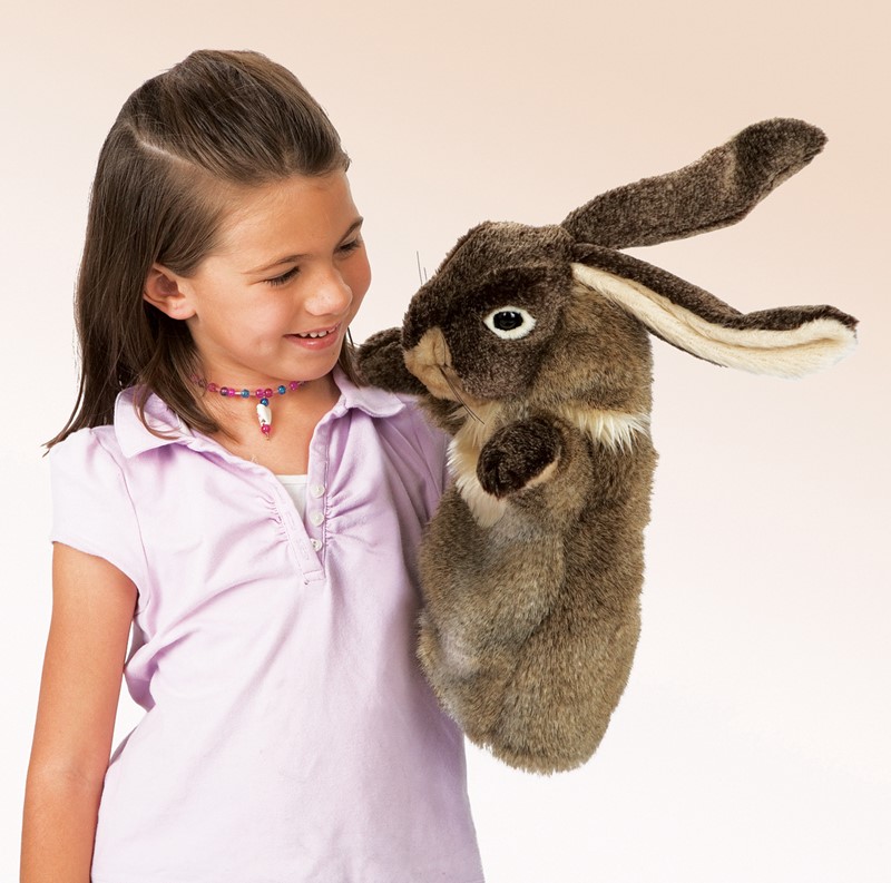 Girl operating a large Folkmanis rabbit hand puppet with brown fur and long ears on her shoulder