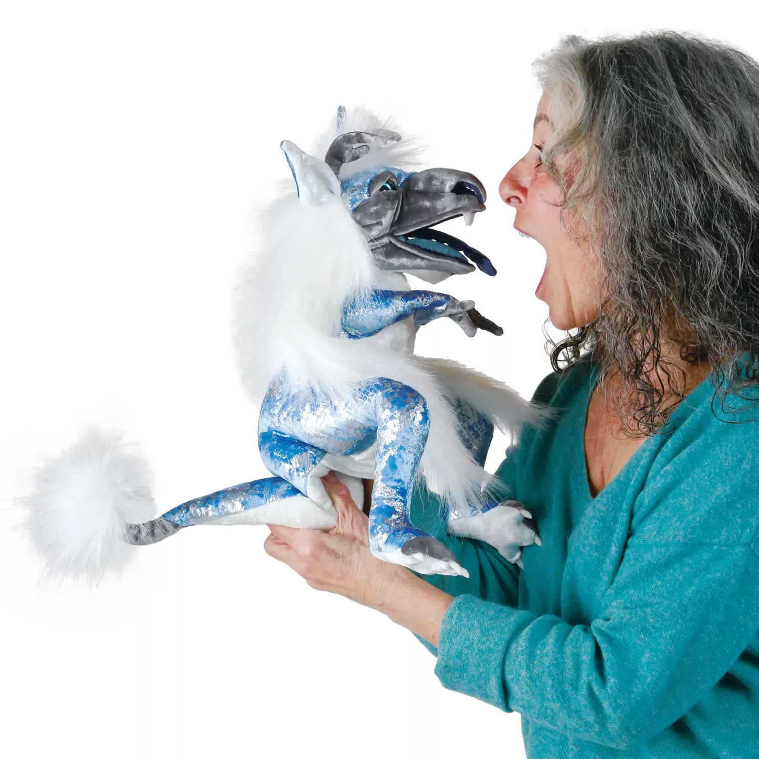 Folkmanis ice dragon hand puppet in blue and silver with white fur, being played by a woman with her mouth open