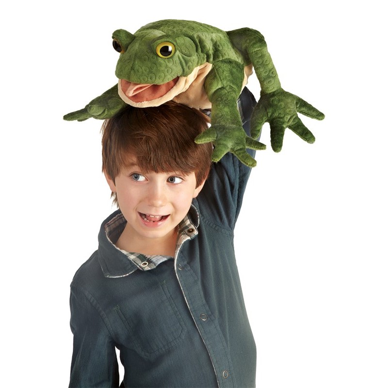 Laughing boy holding a Folkmanis toad hand puppet with an open mouth and green textured surface above his head