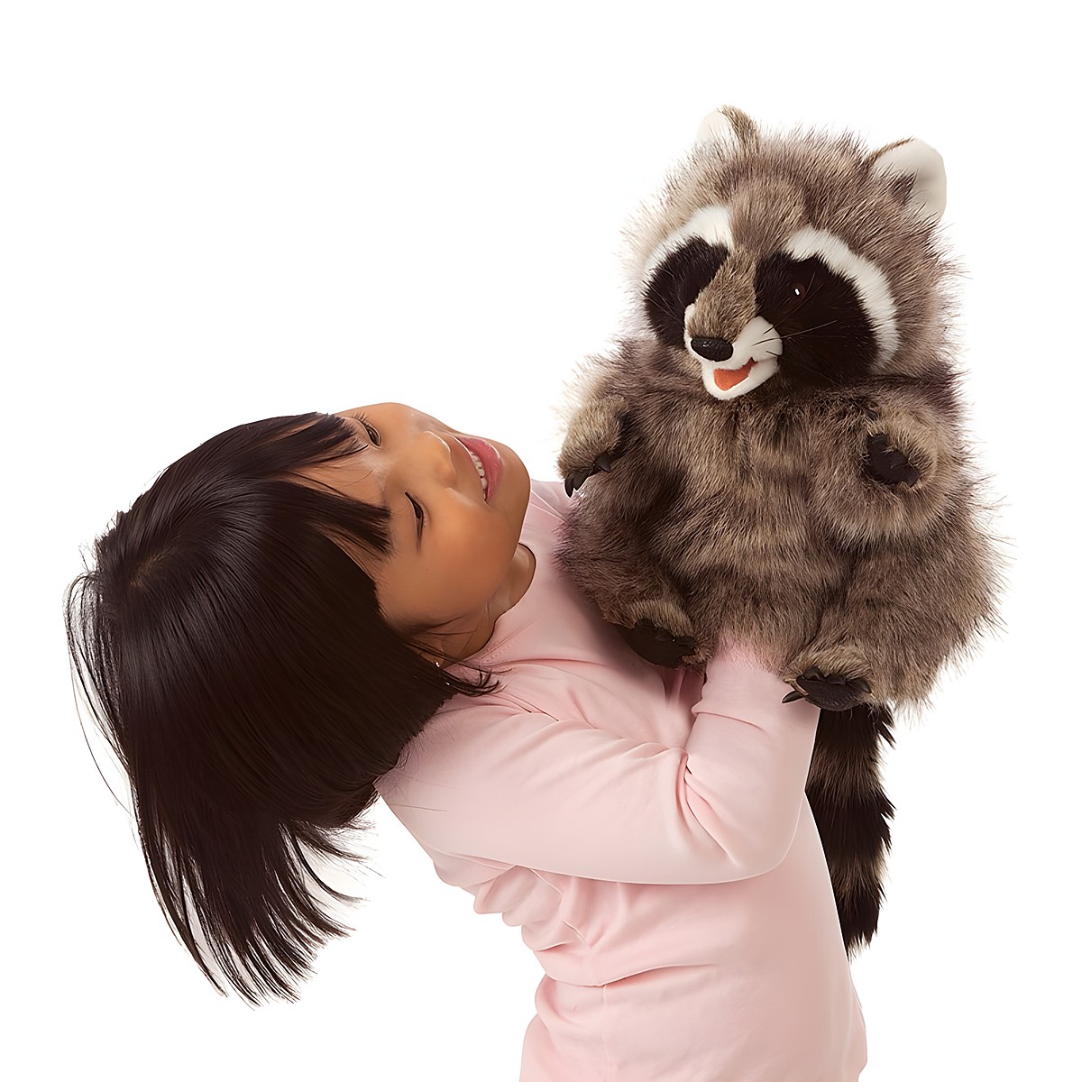 Girl holding a Folkmanis raccoon hand puppet with an open mouth up in the air, grey-brown fur with a black face mask