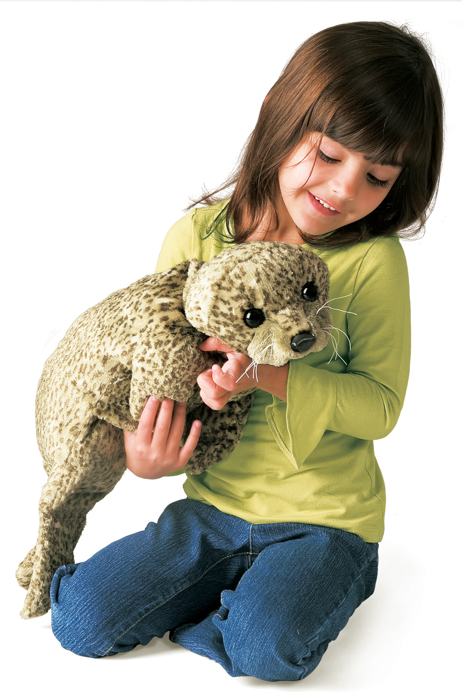 Girl holding the Folkmanis harbor seal baby hand puppet with beige spotted fur texture and white whiskers in both hands