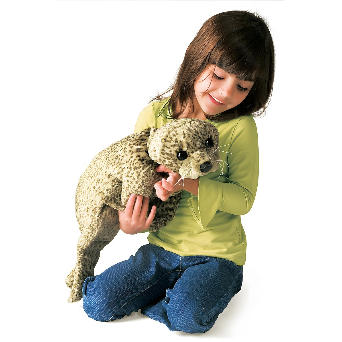 Girl holding the Folkmanis harbor seal baby hand puppet with beige spotted fur texture and white whiskers in both hands