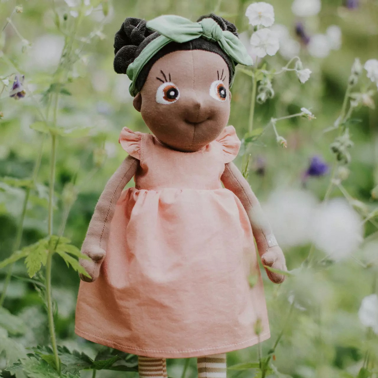 Rubens EcoBuds doll in the pink summer dress with green hairband in a flower meadow