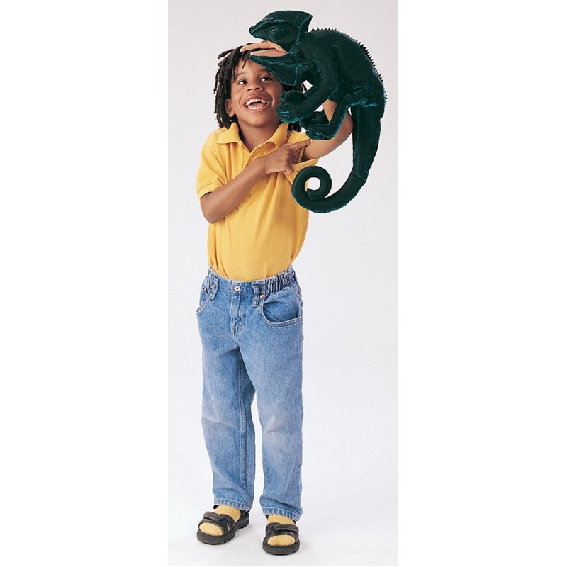 Laughing boy holding a large dark green Folkmanis chameleon hand puppet with a curled tail up in the air