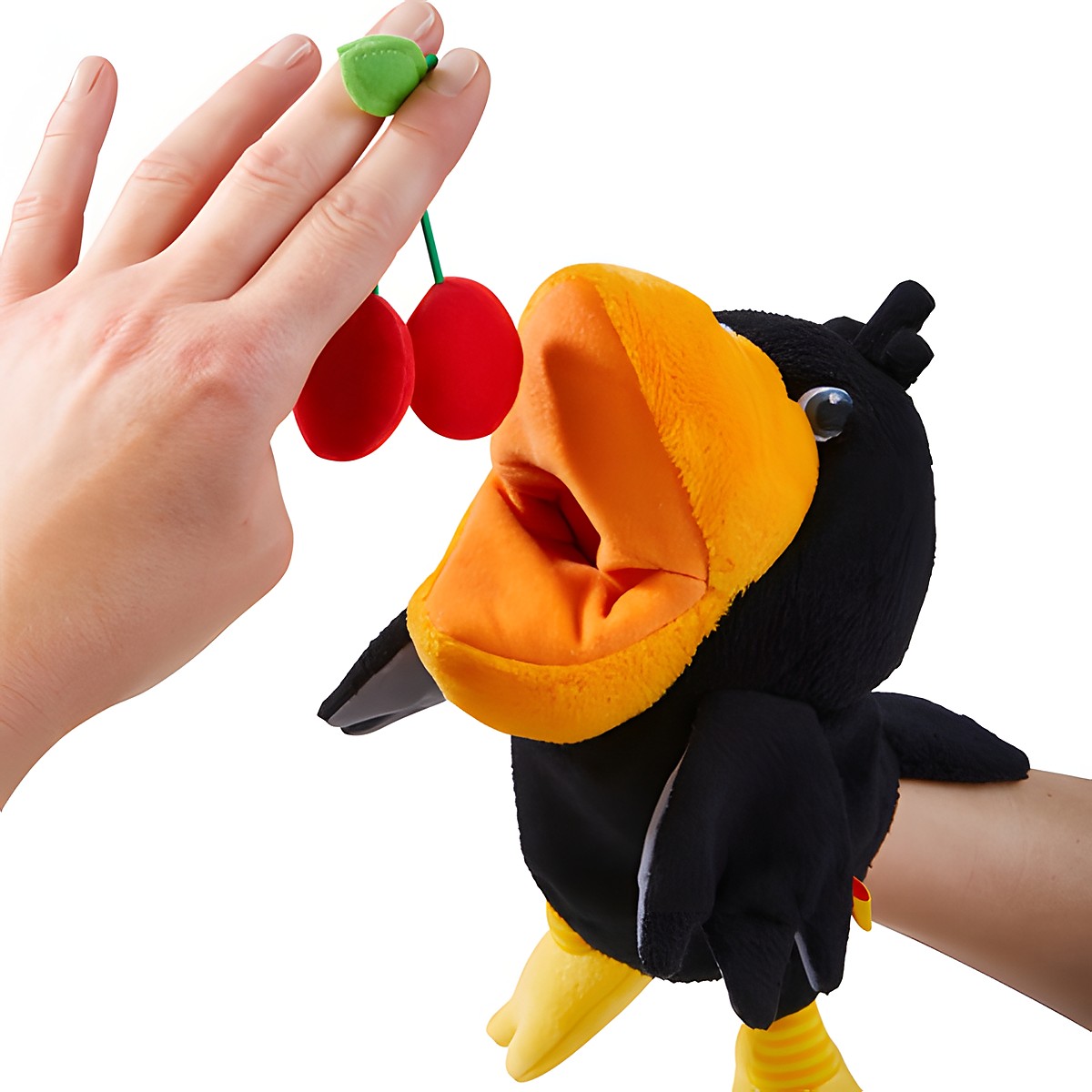 HABA baby hand puppet raven Theo, close-up of a hand holding plush cherries to the raven's beak