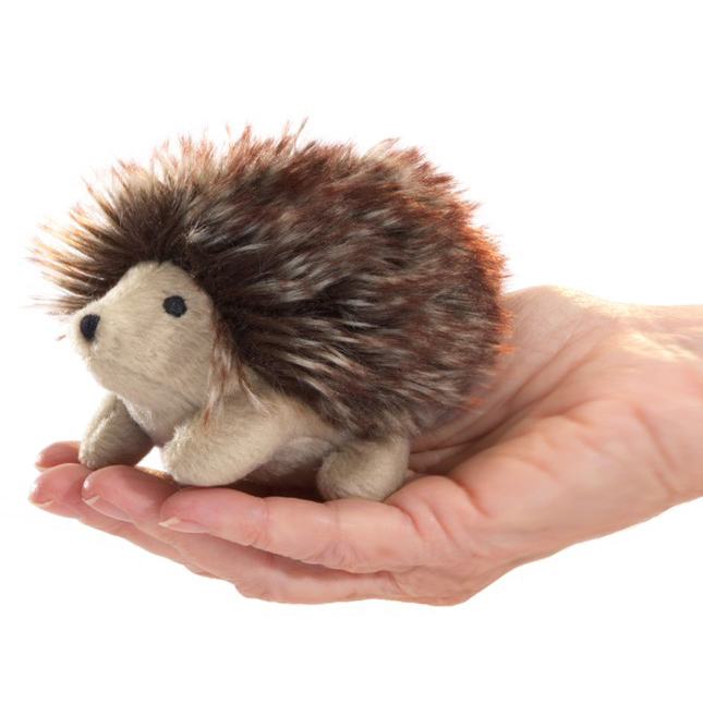 Folkmanis mini hedgehog finger puppet with brown spiny back, lying on a palm, side view