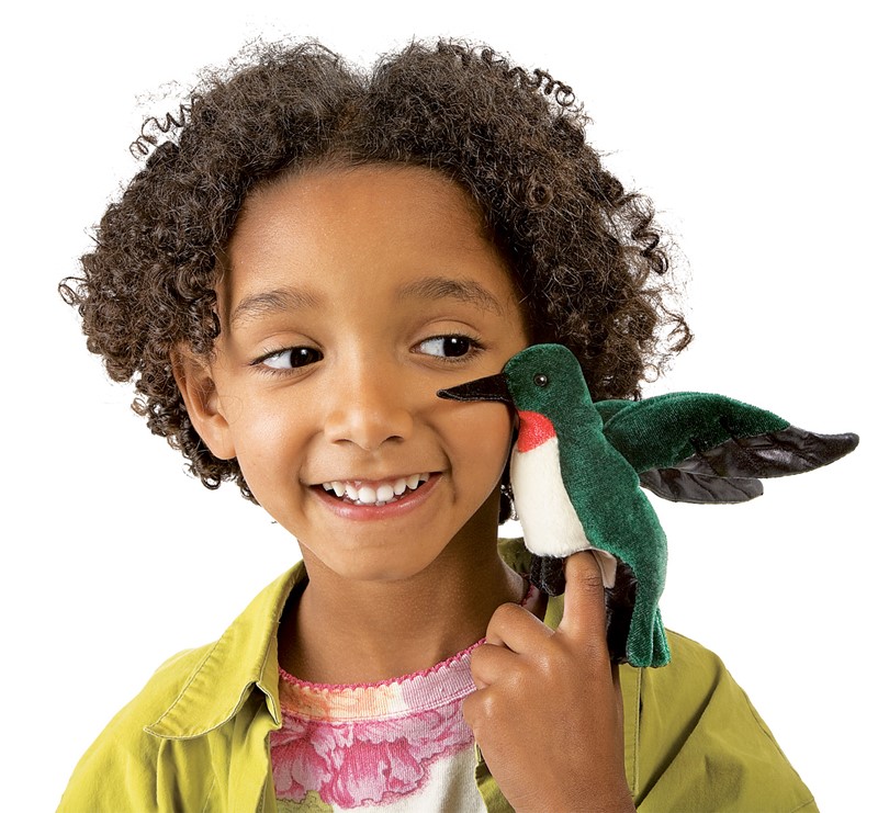 Folkmanis mini hummingbird finger puppet with green plumage and red throat on the finger of a smiling child