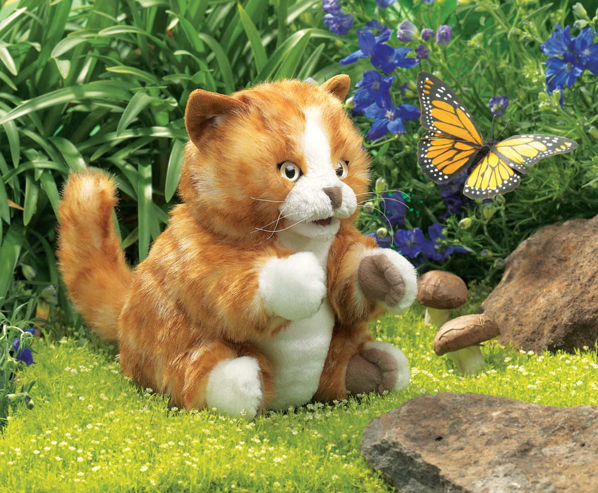 Folkmanis orange tabby kitten hand puppet with white paws, sitting on grass watching a monarch butterfly