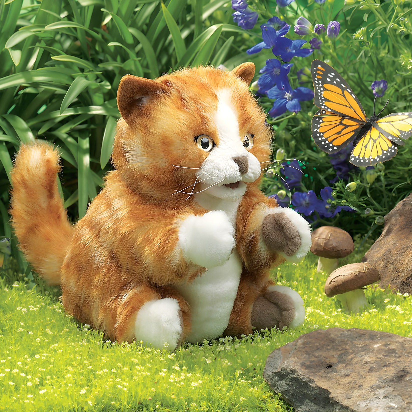 Folkmanis orange tabby kitten hand puppet with white paws, sitting on grass watching a monarch butterfly