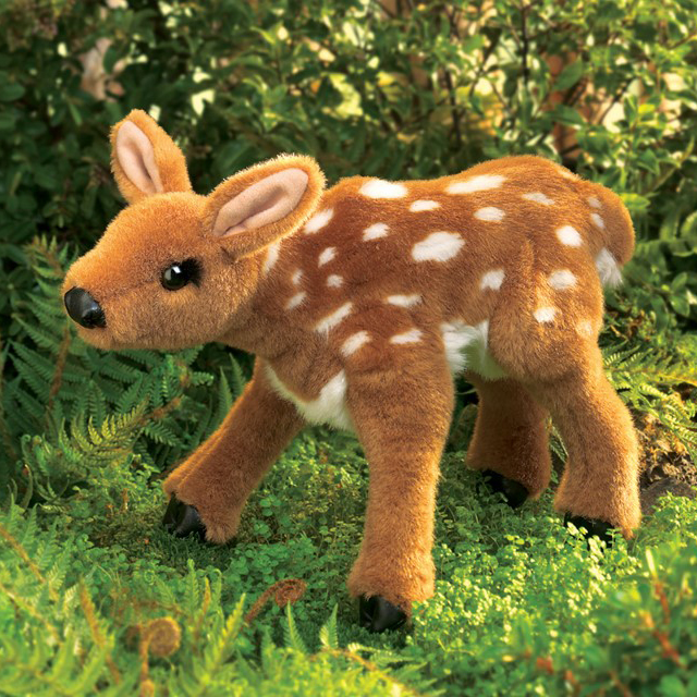 Folkmanis fawn hand puppet in brown plush with white spots, standing on a forest floor, side view