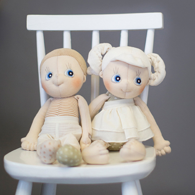 Two Rubens EcoBuds dolls on a white children's chair, Daisy on the right