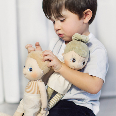Child holding the Rubens EcoBuds doll Iris with green bun in their arms