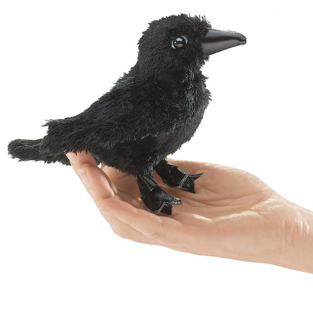 Folkmanis mini raven finger puppet in black sitting on a palm, side view with detailed claws