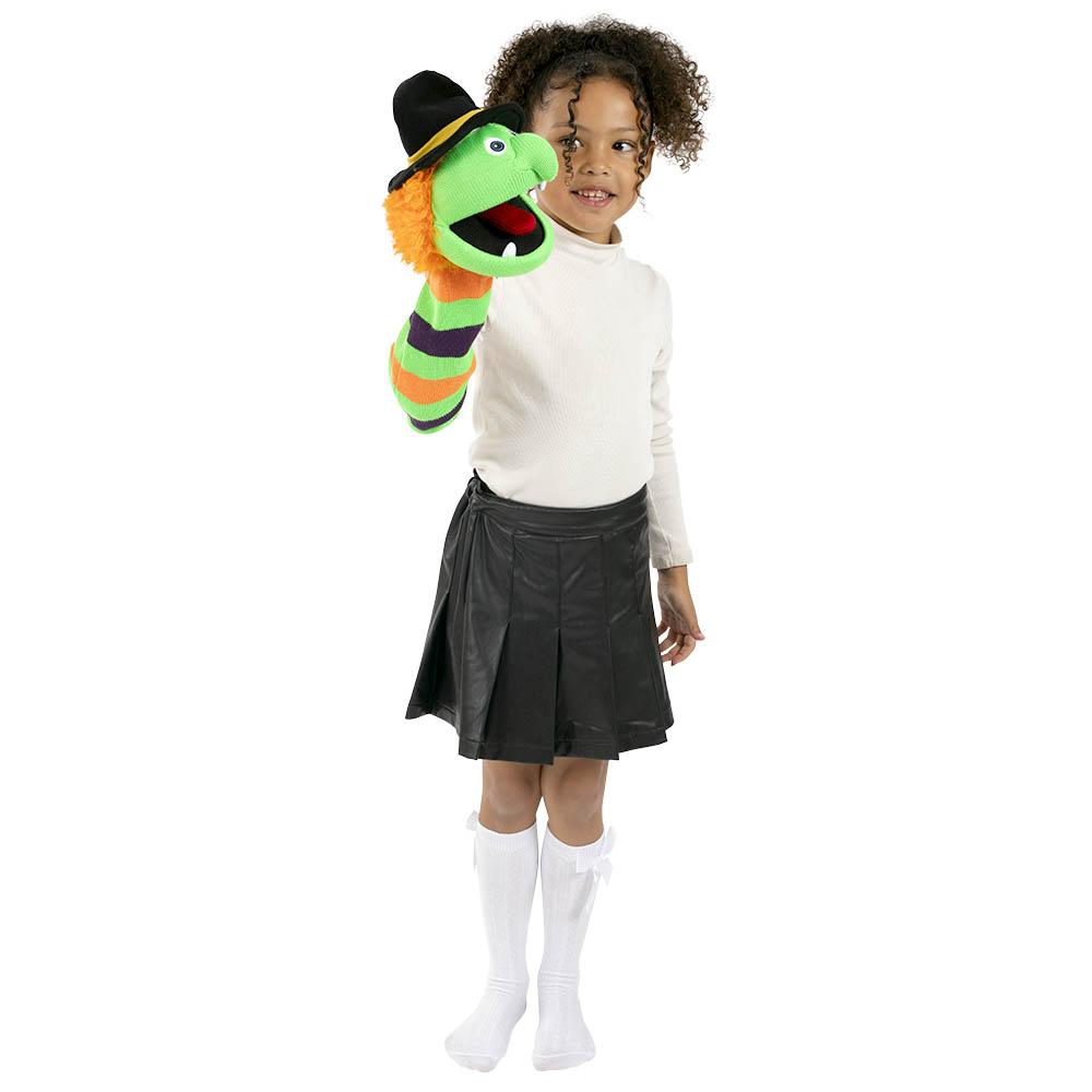 Child playing with the Puppet Company Witch Wilma monster sock puppet, holding the green knitted character with its black witch's hat on one hand