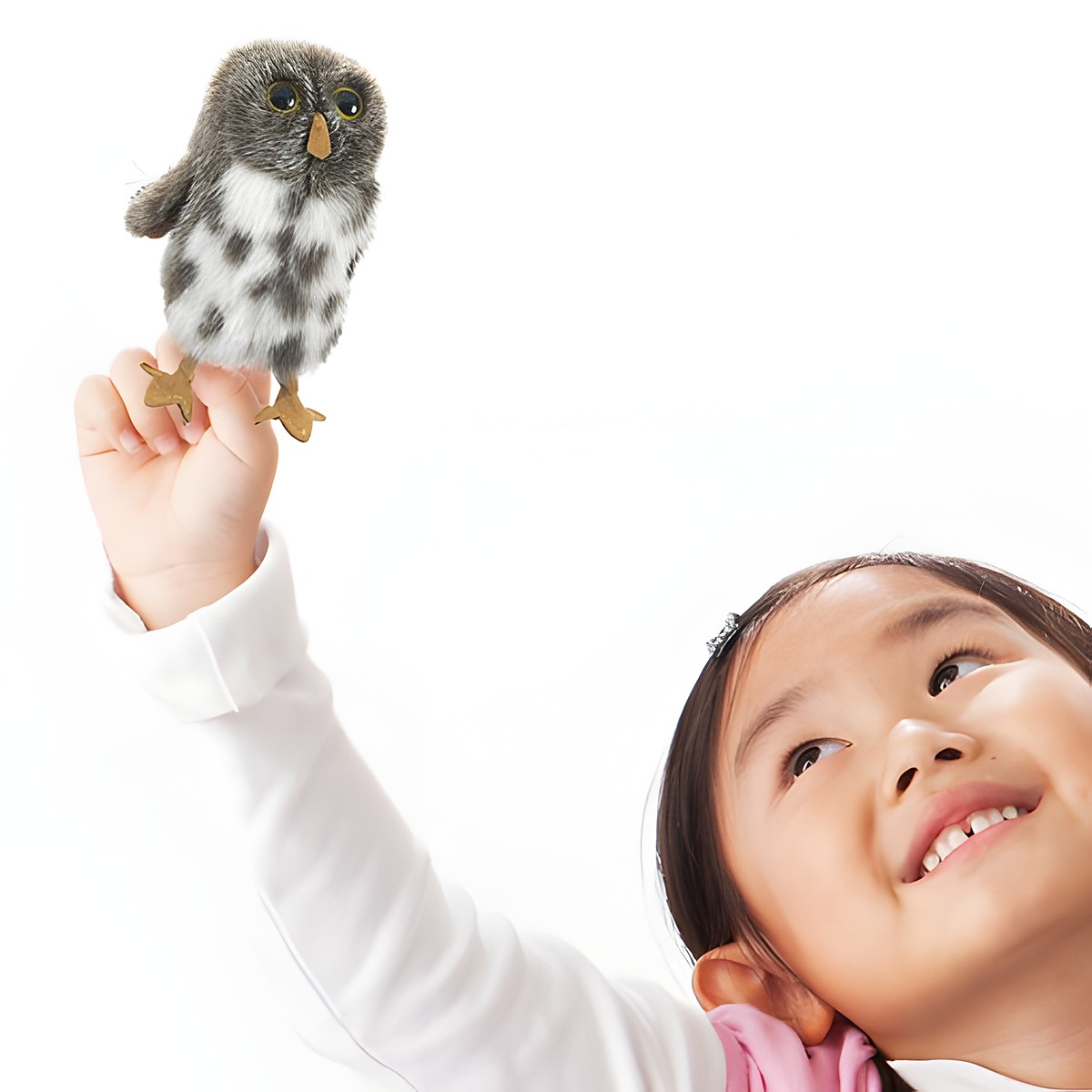 Folkmanis mini Spotted Owl finger puppet grey-and-white spotted, shown on the index finger of a smiling girl