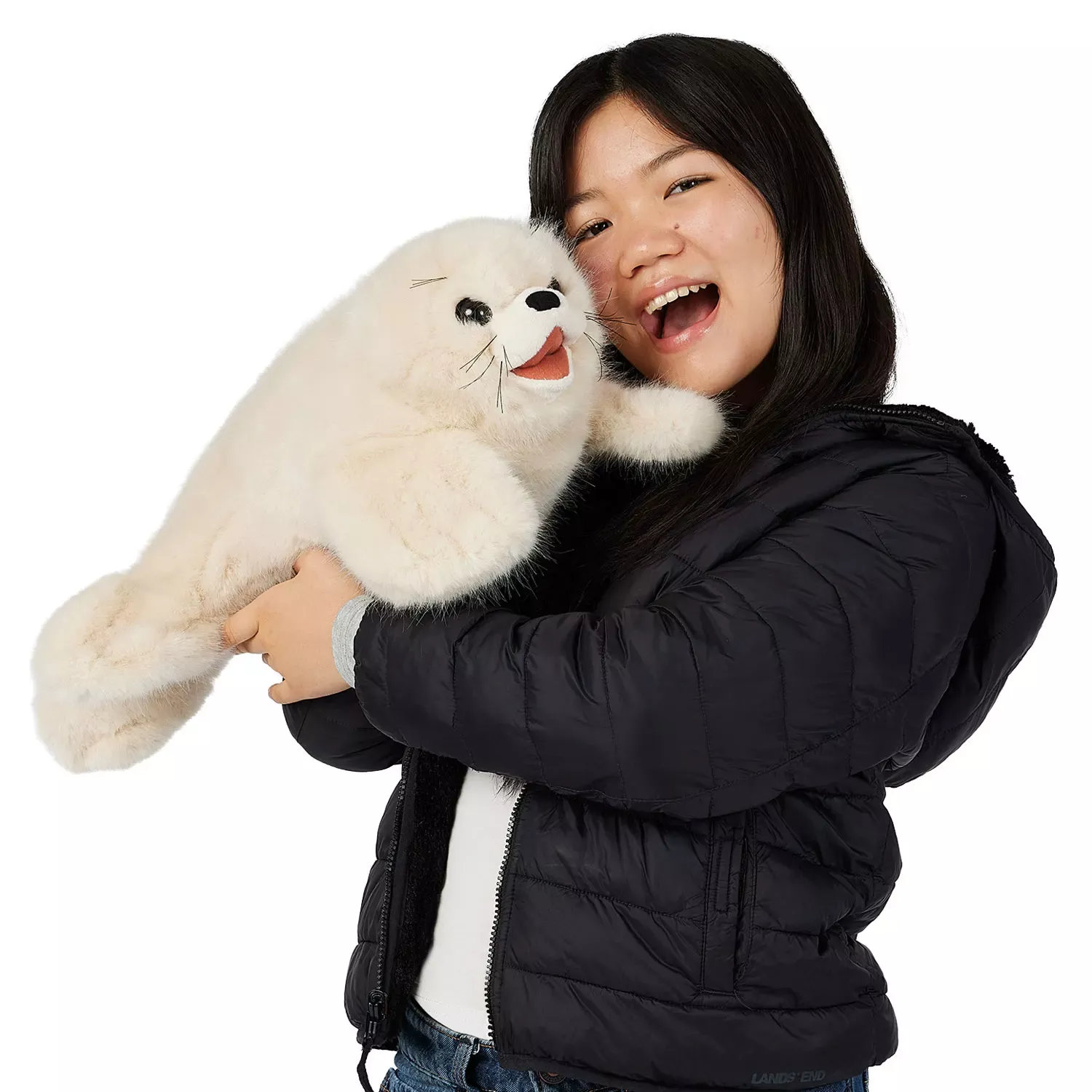 Girl holding a large Folkmanis harp seal pup hand puppet with white plush fur, black eyes and an open mouth in her arms