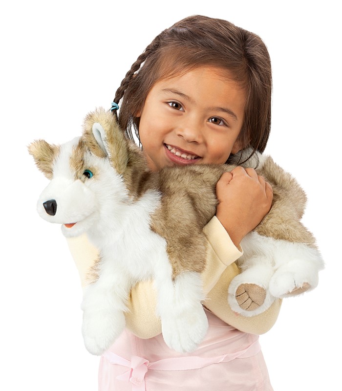 Girl holding the Folkmanis wolf pup hand puppet with grey-and-white plush fur and blue eyes in her arms