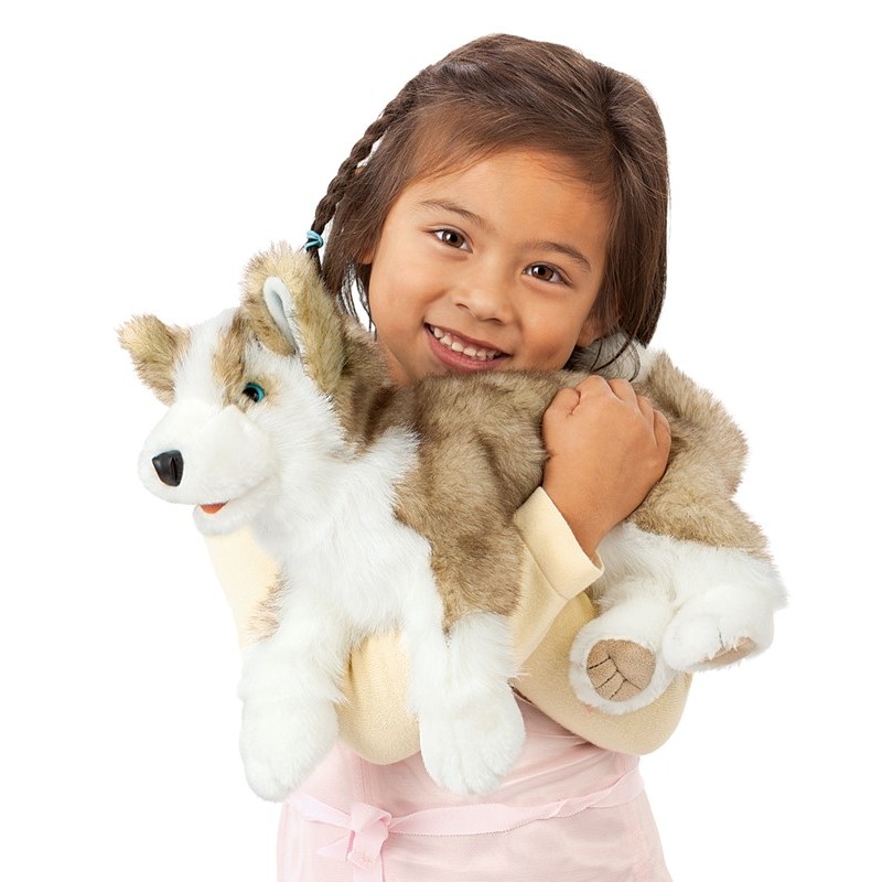 Girl holding the Folkmanis wolf pup hand puppet with grey-and-white plush fur and blue eyes in her arms