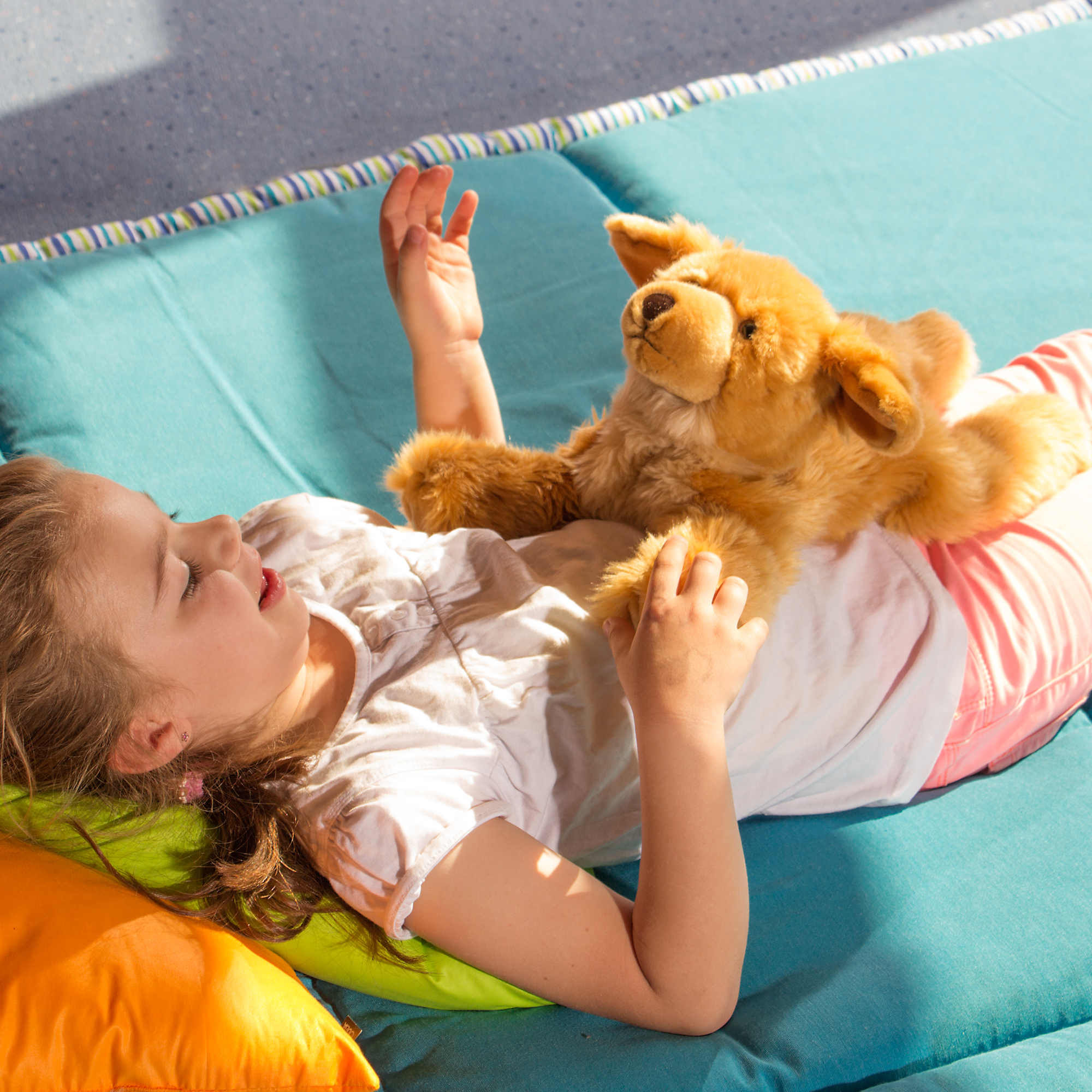 Child relaxing with the Joyk empathy doll Brando lying on their belly