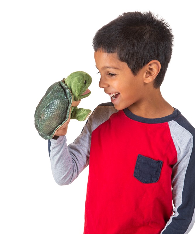 Boy holding the Folkmanis little turtle hand puppet with open mouth on his hand, laughing at it
