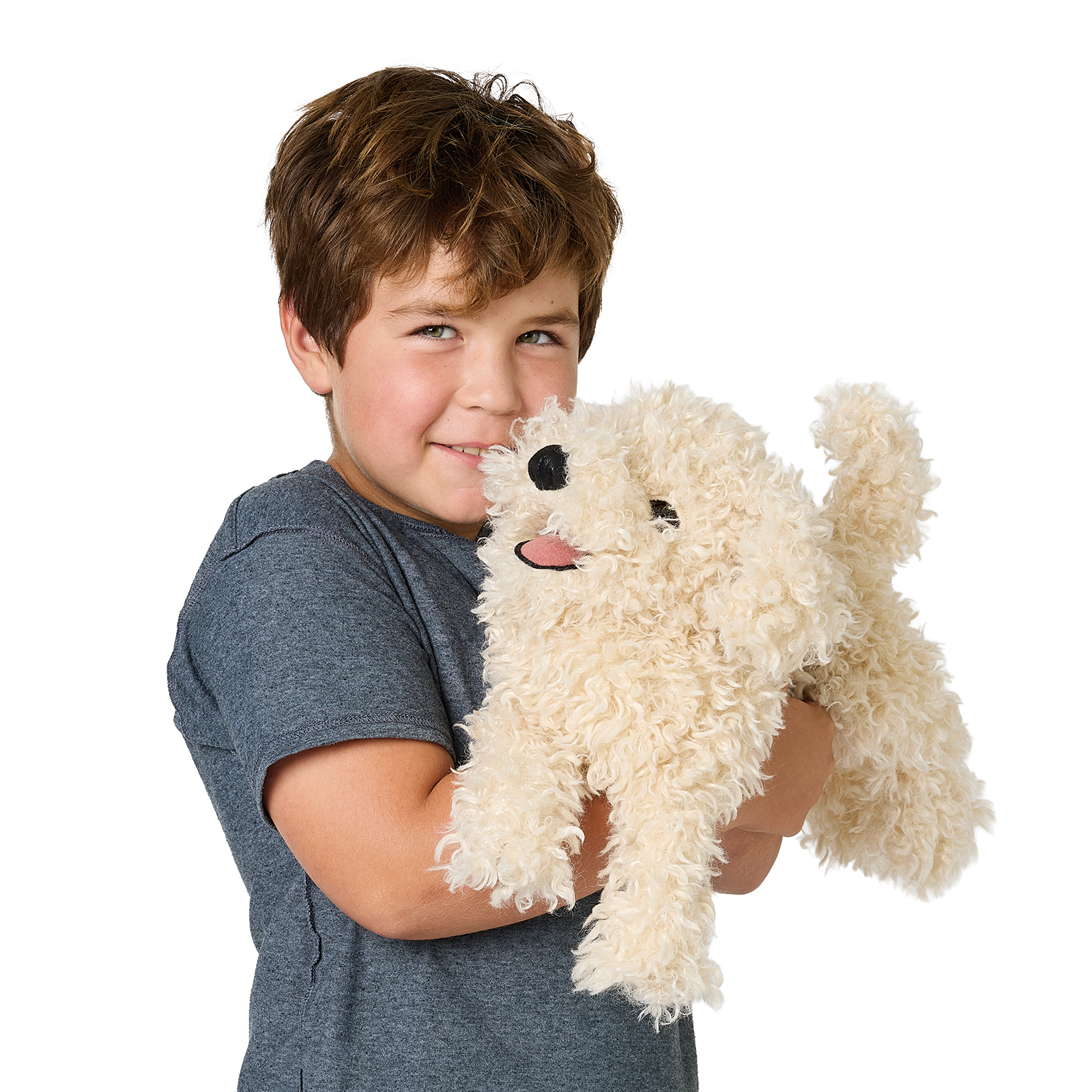 Smiling boy holding the Folkmanis white poodle puppy hand puppet with curly cream fur and outstretched tongue against a white background
