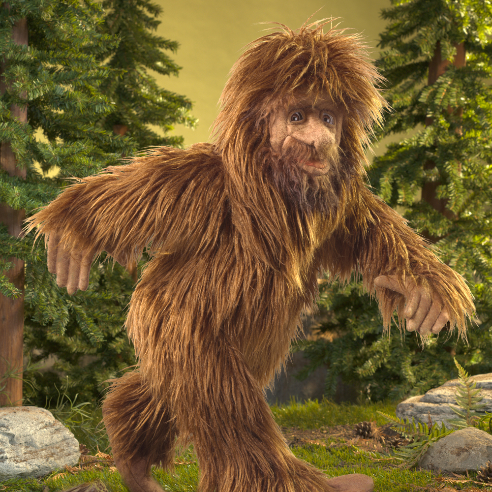 Folkmanis Sasquatch hand puppet with shaggy brown fur, outstretched arms and a detailed face, set against a forest backdrop
