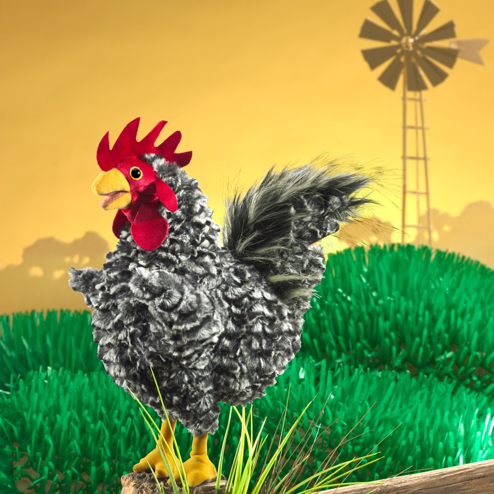 Folkmanis hand puppet rooster with grey-white curly plumage, red comb and yellow claws, perched on a wooden post