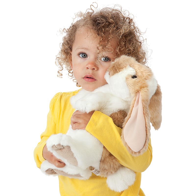 Small girl holding the Folkmanis standing lop rabbit hand puppet with beige-and-white fur and long floppy ears in her arms