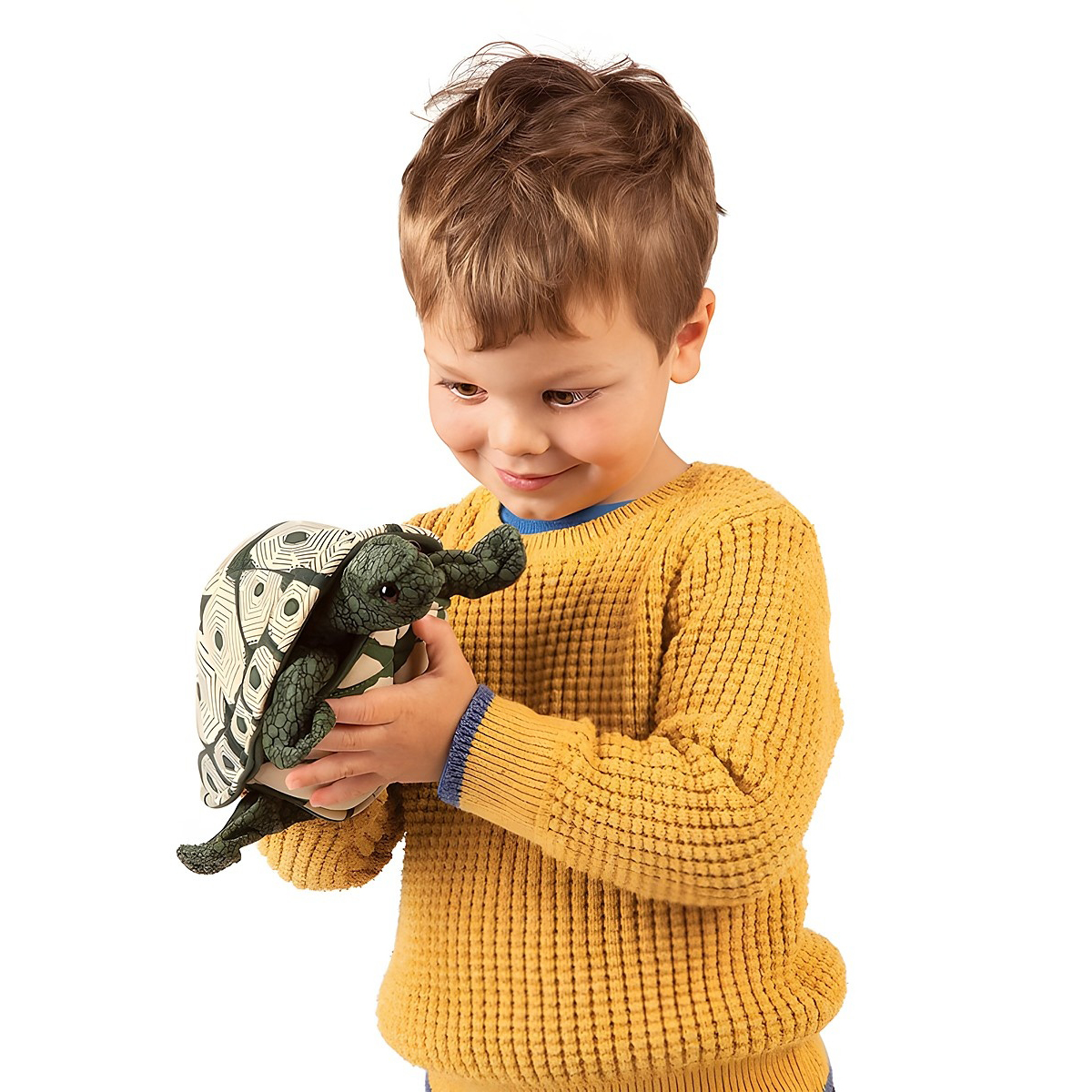 Boy in a yellow jumper holding the Folkmanis tortoise hand puppet with a patterned shell in both hands